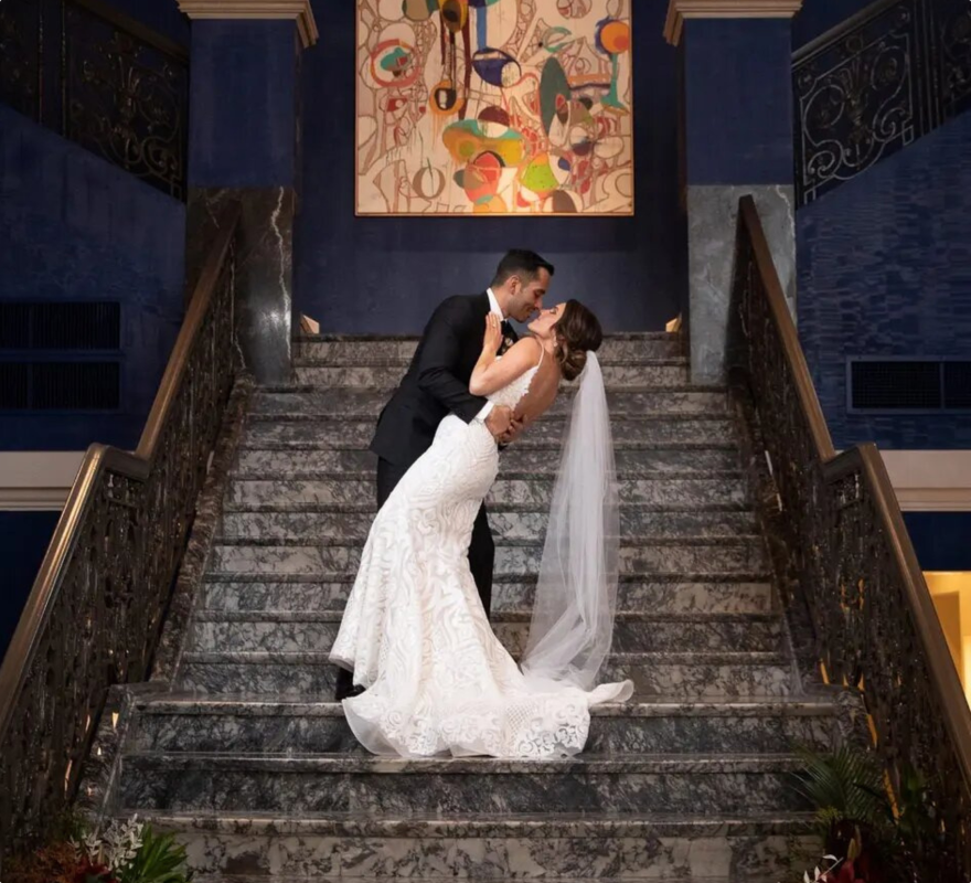 a bride and groom standing on the stairs kissing