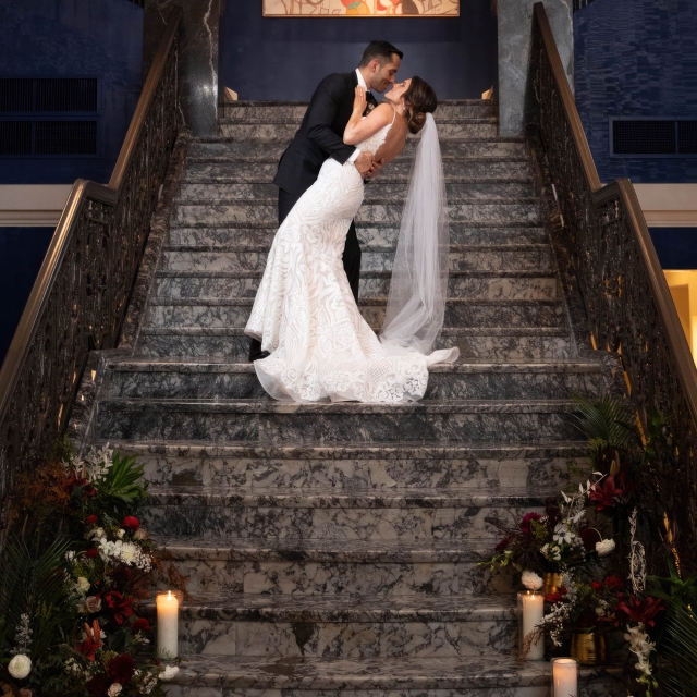 A bride and groom preparing for a kiss while standing on the stairs at The Marker