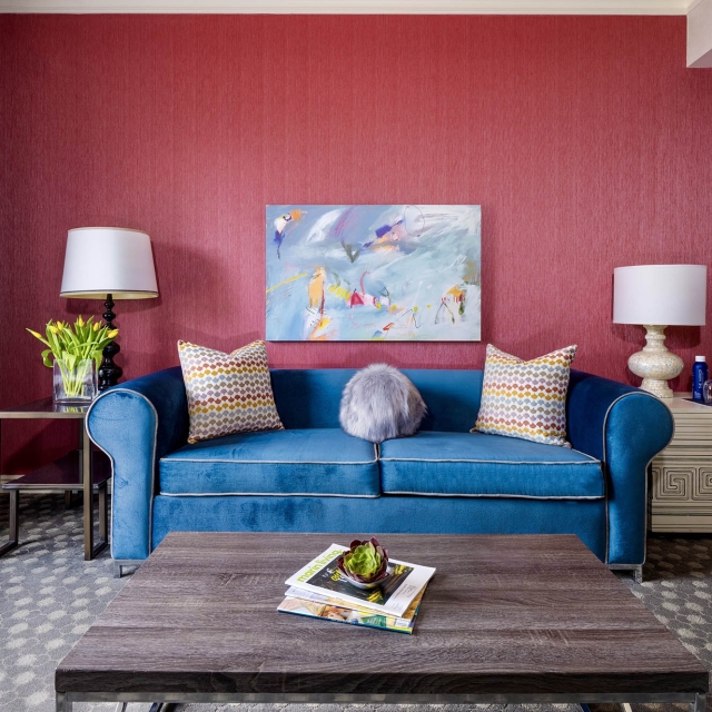 A large blue couch sitting in front of a red wall at The Marker